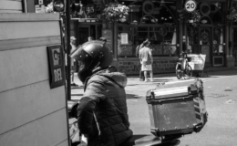 Pengendara kurir berhelm di atas skuter di jalan kota